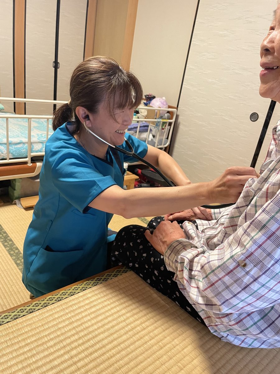 ご自宅の和室で聴診器を当ててご利用者さまを診るいろはのスタッフ